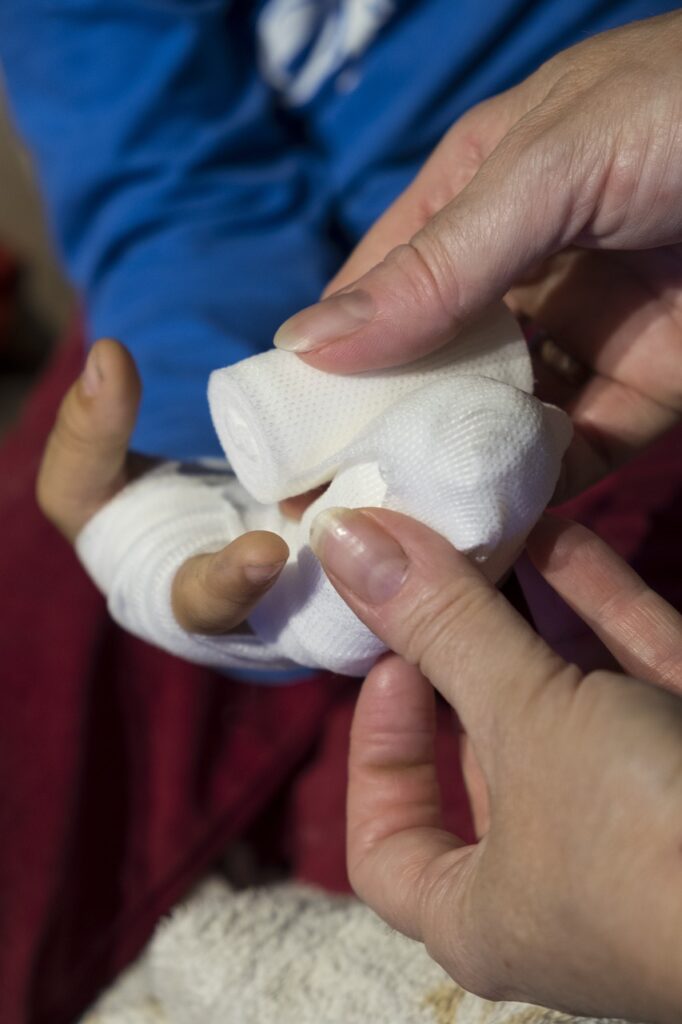 Photo of a person bandaging someone else's hand because of an injury